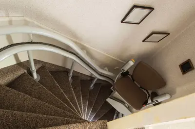 Downward angle of a brown-upholstered curved stairlift in Lakewood Ranch.